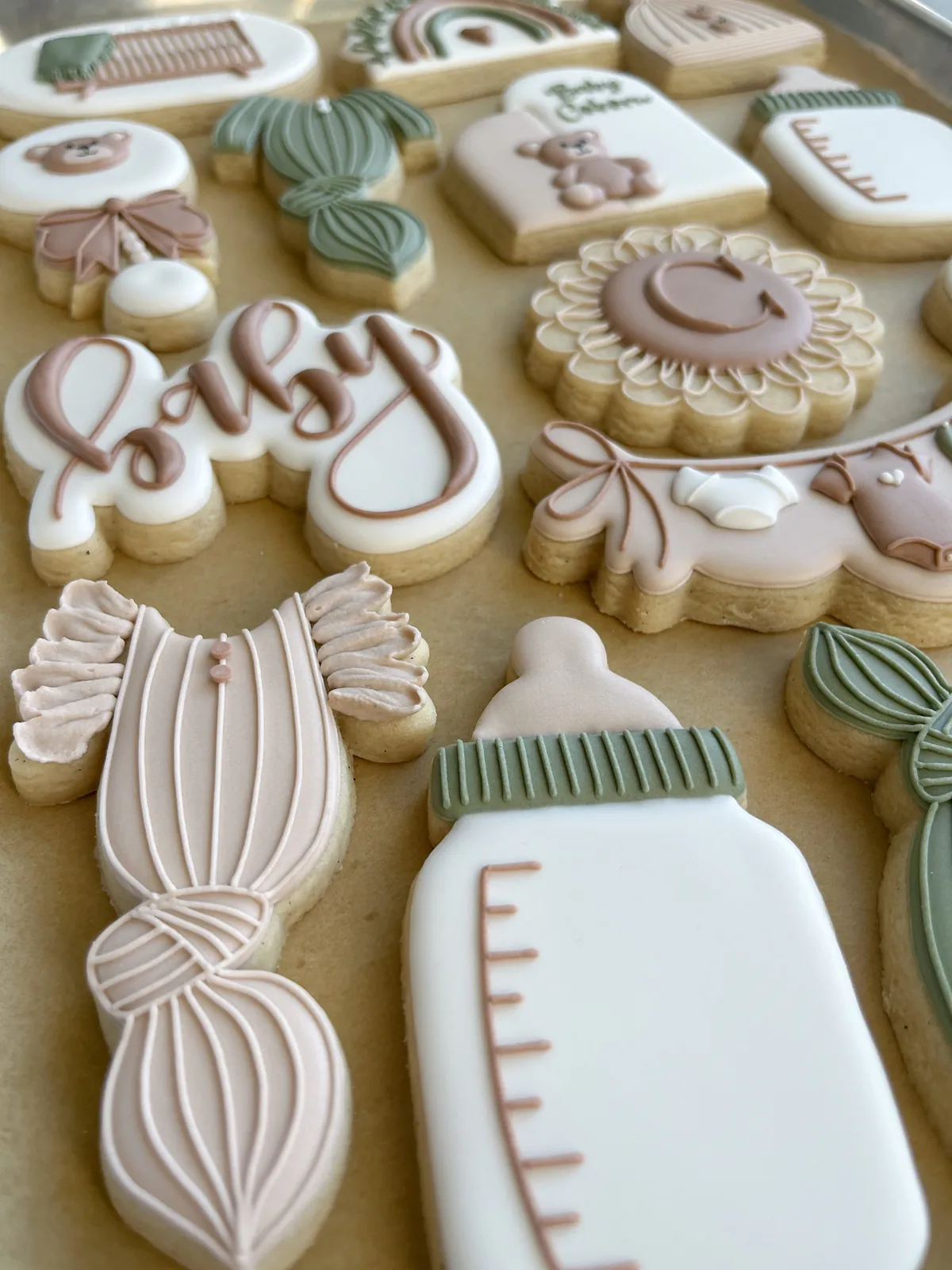 Detailed baby-shower cookies: pram, bottle, onesie, rattle and a scalloped Baby plaque
